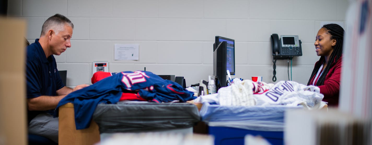 AUTH090114 * 20035859A * 964956 * Mark Vancleave - mark.vancleave@startribune.com * Twins authenticator Steven Bantle collects and tags game memorabilia during a Twins-Royals game Sun. Aug. 17, 2014 at Target Field. [Twins authenticator Steven Bantle and authentication coordinator Venika Streeter work through piles of memorabilia awaiting authentication before Sunday's game in the Target Field mail room.]