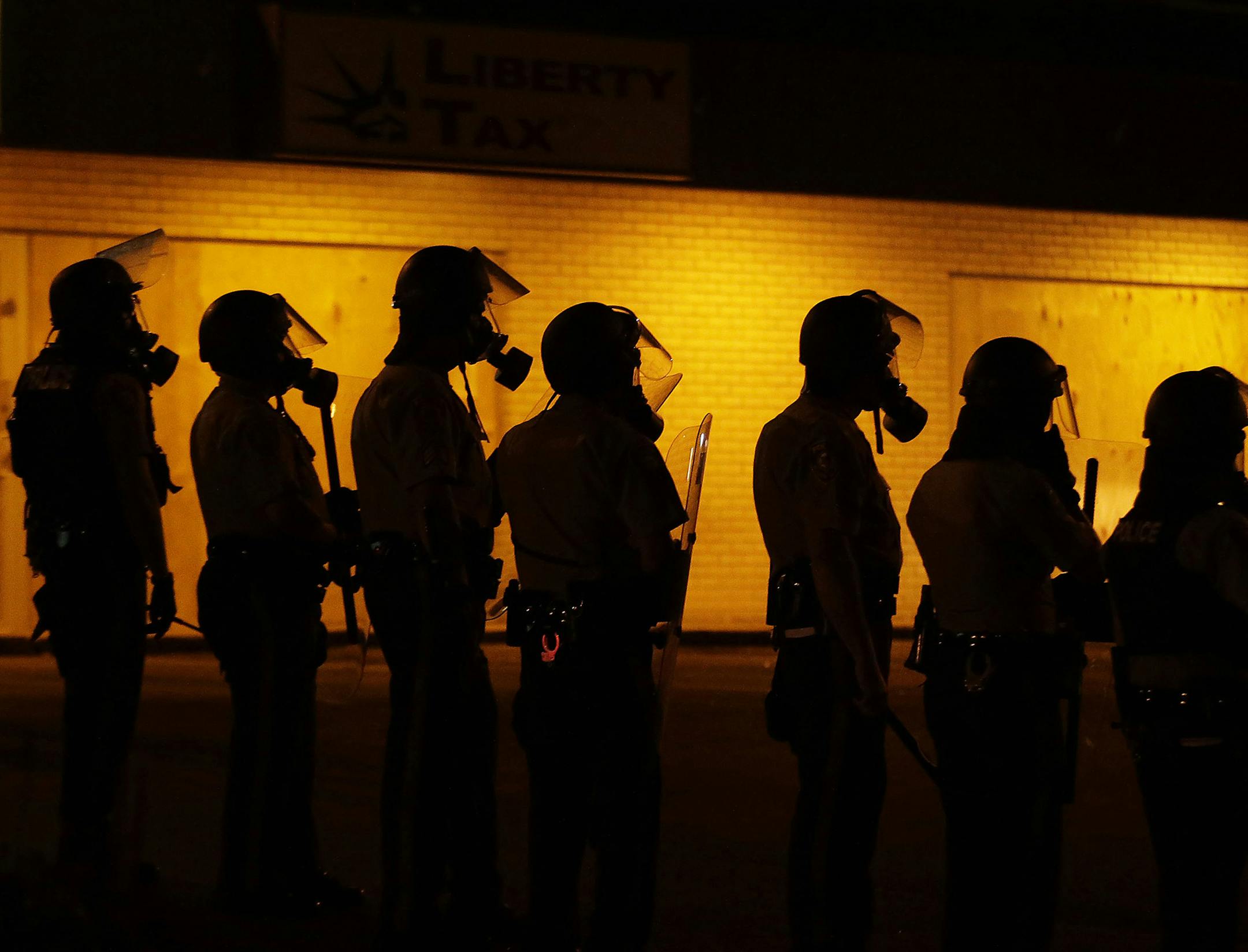 FILE - In this Aug. 17, 2014 file photo, police wait to advance after tear gas was used to disperse a crowd during a protest for Michael Brown, who was killed by a police officer Aug. 9 in Ferguson, Mo. The Ferguson City Council, set to meet Tuesday, Sept. 9, 2014, for the first time since the fatal shooting of Brown, said it plans to establish a review board to help guide the police department and make other changes aimed at improving community relations. (AP Photo/Charlie Riedel, File) ORG XMI