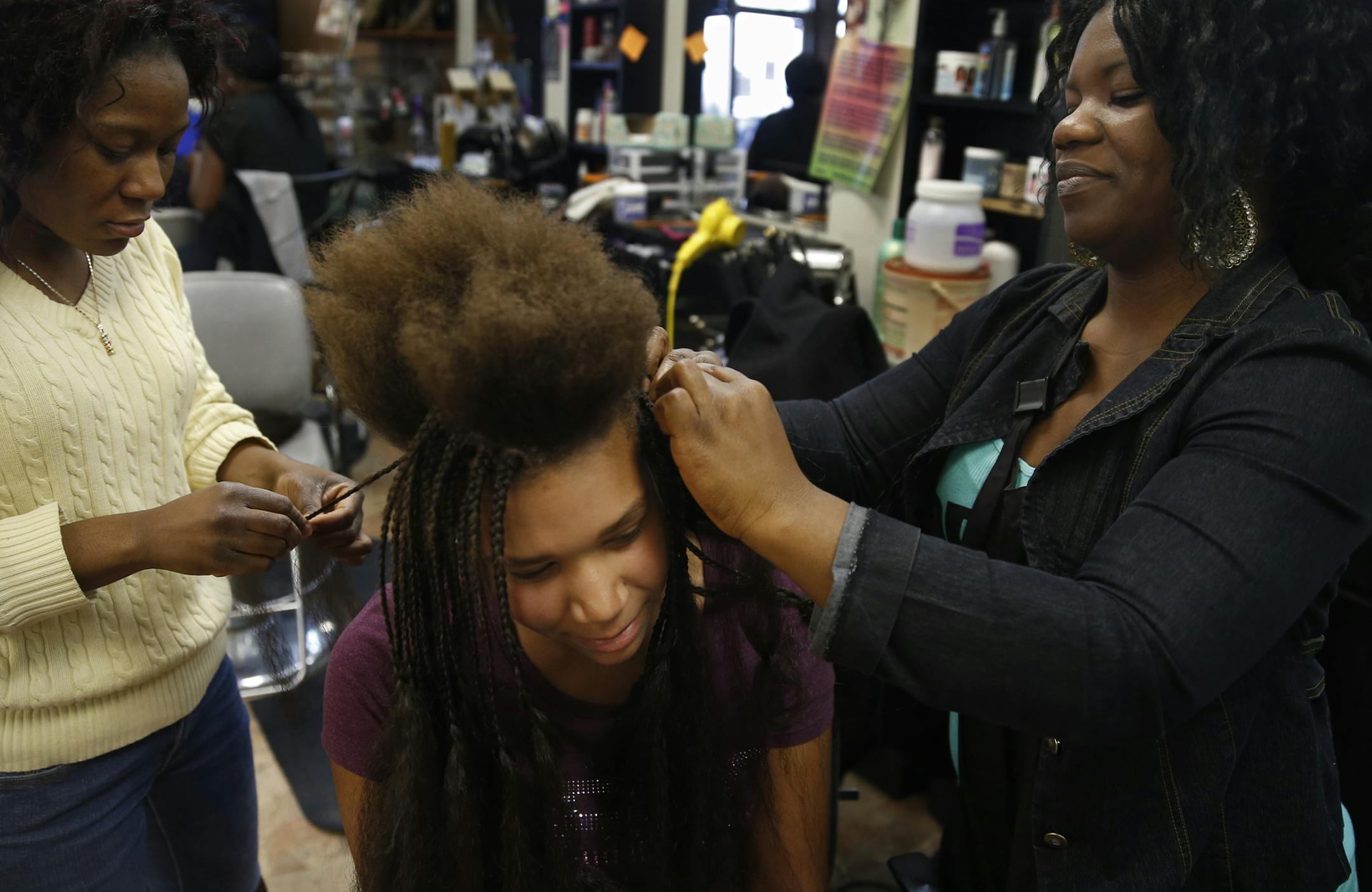 Rose Smith, left, and Thelma Juah, both Liberian hairdressers, worked with Grace Flanigan, 12, on a hair-extension makeover at Elegant Hair Design in Brooklyn Park.