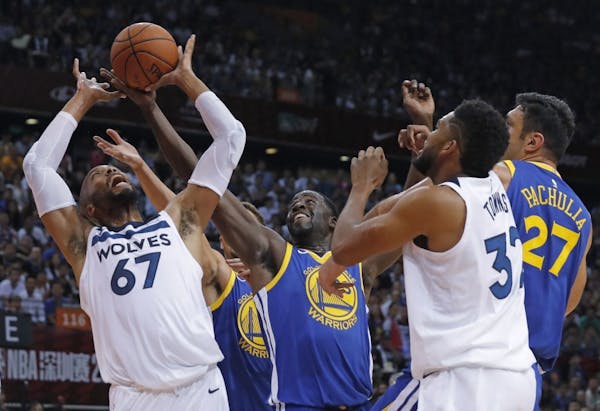 The Timberwolves' Taj Gibson, left, fought for the ball with the Warriors' Draymond Green, center, during the NBA Global Games in Shenzhen, south Chin