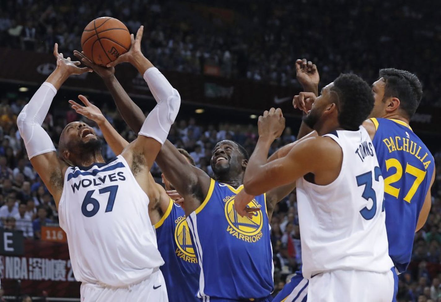 The Timberwolves' Taj Gibson, left, fought for the ball with the Warriors' Draymond Green, center, during the NBA Global Games in Shenzhen, south China's Guangdong province, on Thursday.