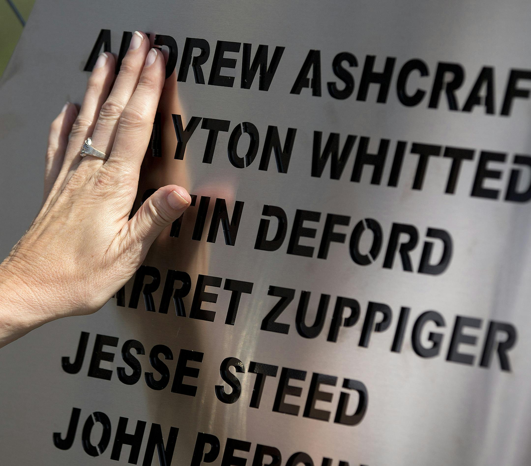 Linda Lambert places her hand across a plaque hanging on the fence outside the Granite Mountain Interagency Hotshot Crew fire station, Tuesday, July 2, 2013 in Prescott, Ariz. The plaque holds the names of the 19 firefighters killed Sunday, by an out-of-control blaze near Yarnell, Ariz. Lambert is the aunt of firefighter Andrew Ashcraft. (AP Photo/Julie Jacobson) ORG XMIT: MIN2013070213125022