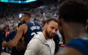 Warriors guard Stephen Curry, injured and in street clothes, congratulates Anthony Edwards after the Wolves' victory.
