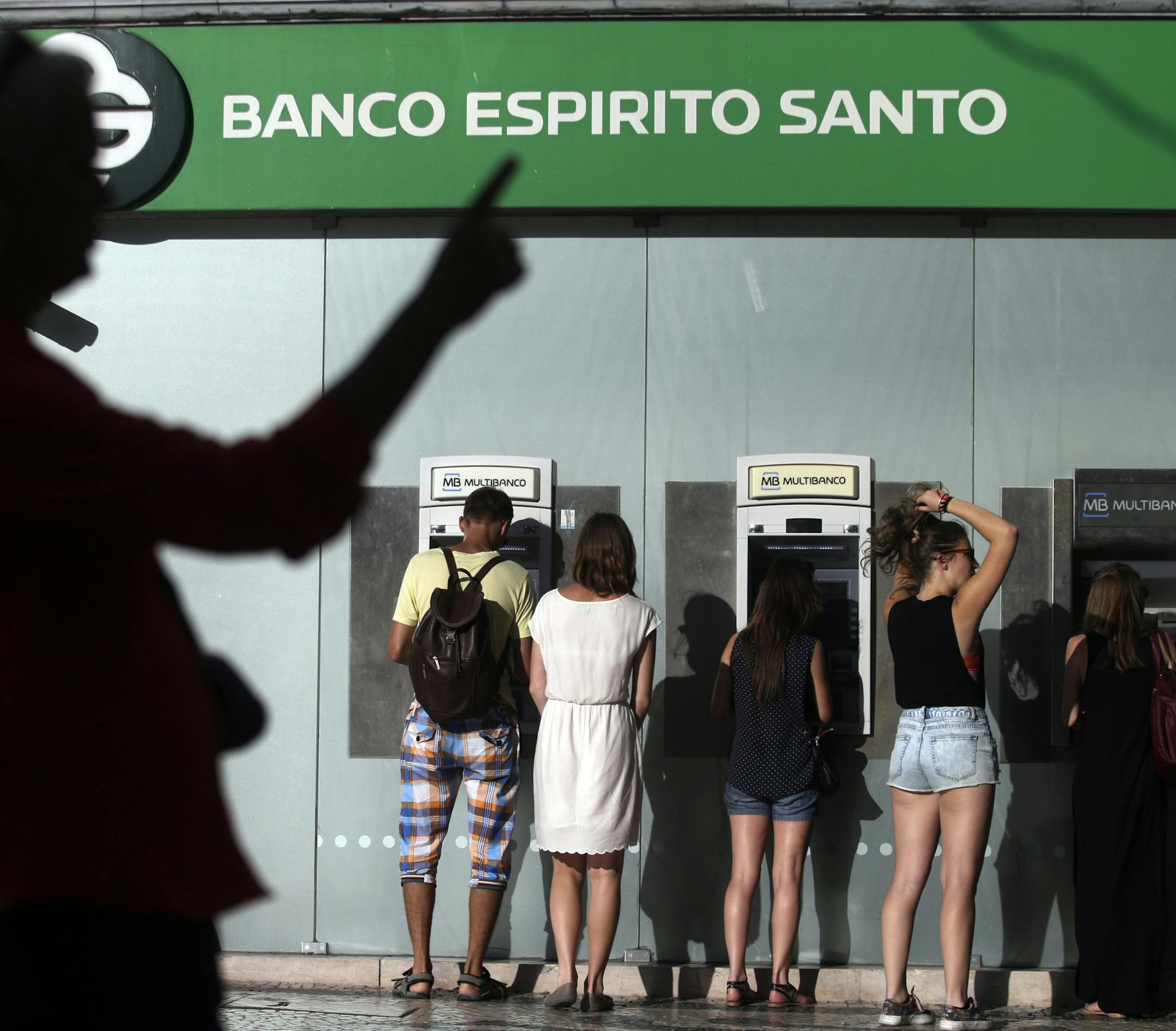 In this July 28, 2014 photo, people use ATMs at a branch of Portuguese bank Banco Espirito Santo in Lisbon. The Espirito Santo family business survived wars, dictatorship, revolution and family feuds for almost 150 years. Now, one of Europe's last banking dynasties is being stripped of its wealth and influence amid accounting irregularities, huge unreported debts, and a police investigation. (AP Photo/Francisco Seco)