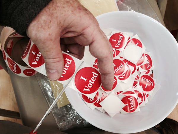 Mike Wilson cut up vote stickers as he waits to help voters feed their ballots into the machines