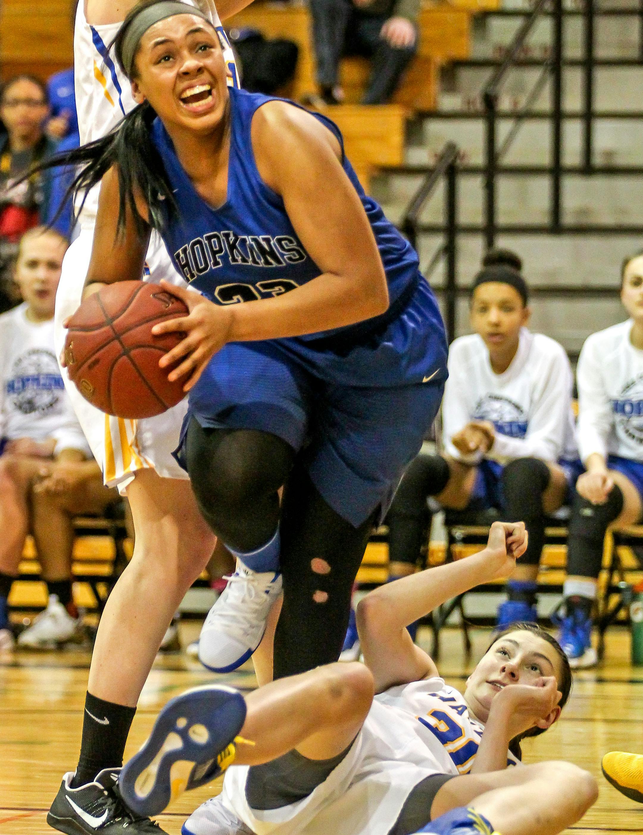 Dlayla Chakolis steps over Kalie Theisen on her way to the basket in Hopkinsí 81-74 victory over Wayzata in the Class 4A Region 6 girlsí basketball final at Minneapolis Roosevelt High School. Chakolis scored 14 points for the Royals. Photo by Mark Hvidsten, SportsEngine