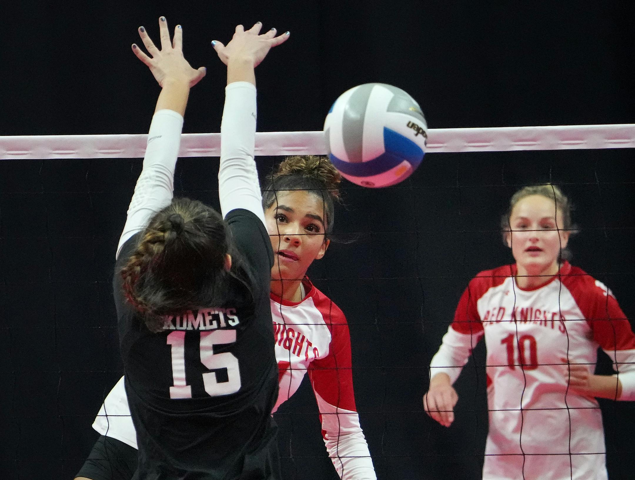 Benilde-St. Margaret's Sierre Lumpkin (24) spikes a shot past Kasson-Mantorville's Sophie Sutton (15) as Benilde-St. Margaret's Lily Eigner (10) looks on during Class 3A volleyball semifinals Friday, Nov. 11, 2022 at Xcel Energy Center in St. Paul, Minn. ]
