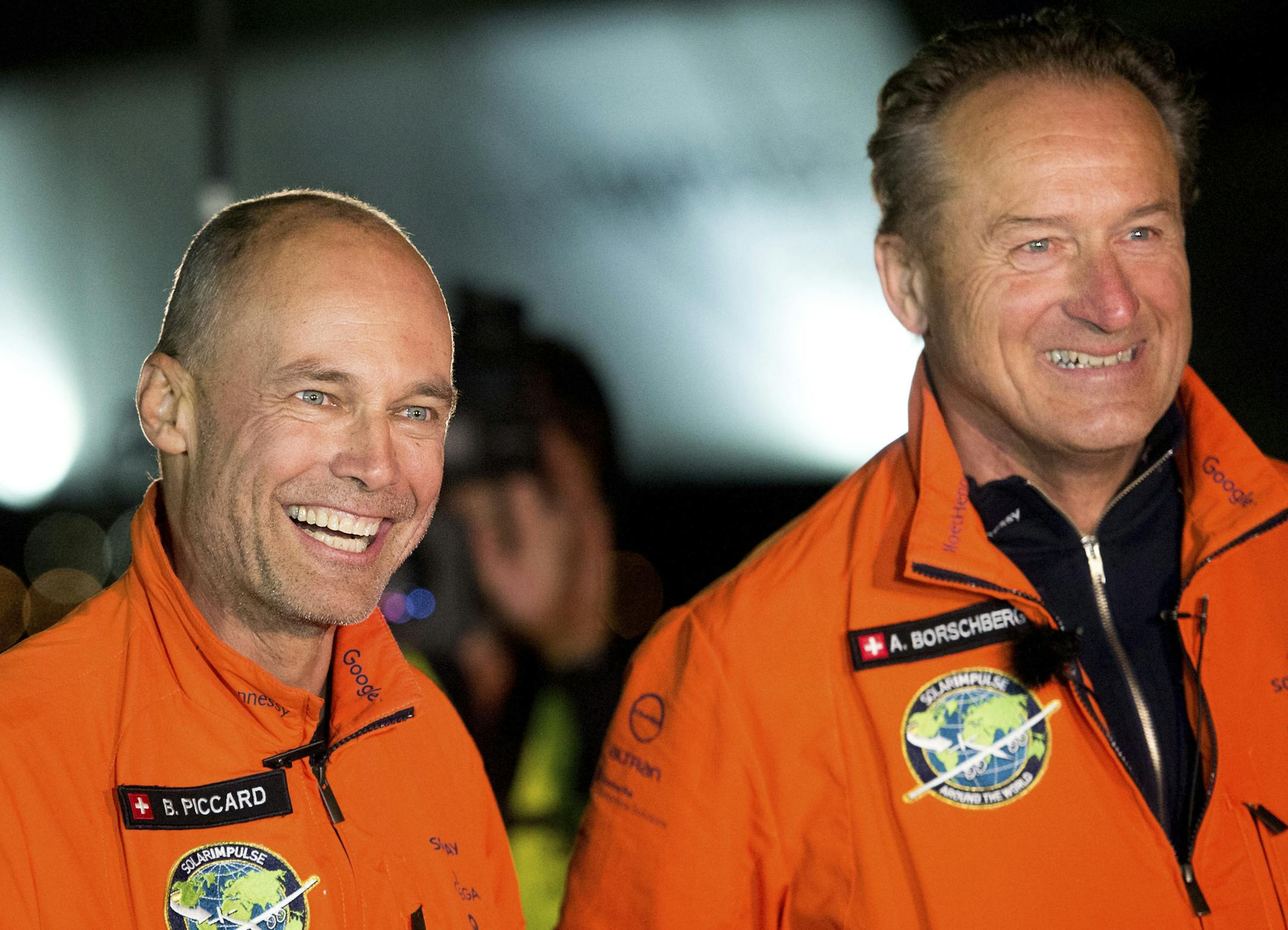 Solar Impulse 2 pilots Bertrand Piccard, left, and Andre Borschberg celebrate after Piccard landed their solar-powered plane at Moffett Field in Mountain View, Calif., on Saturday, April 23, 2016. The solar-powered airplane landed in California on Saturday, completing a risky, three-day flight across the Pacific Ocean as part of its journey around the world. (AP Photo/Noah Berger)
