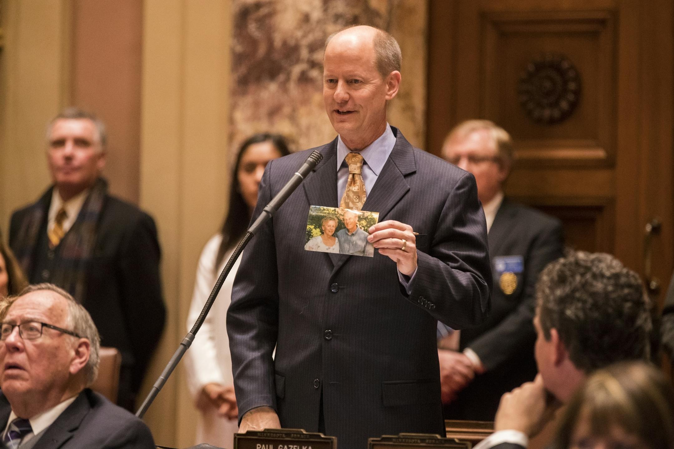 Senate Majority Leader Paul Gazelka holds a photo of his parents as he speaks in the Minnesota Senate chambers.