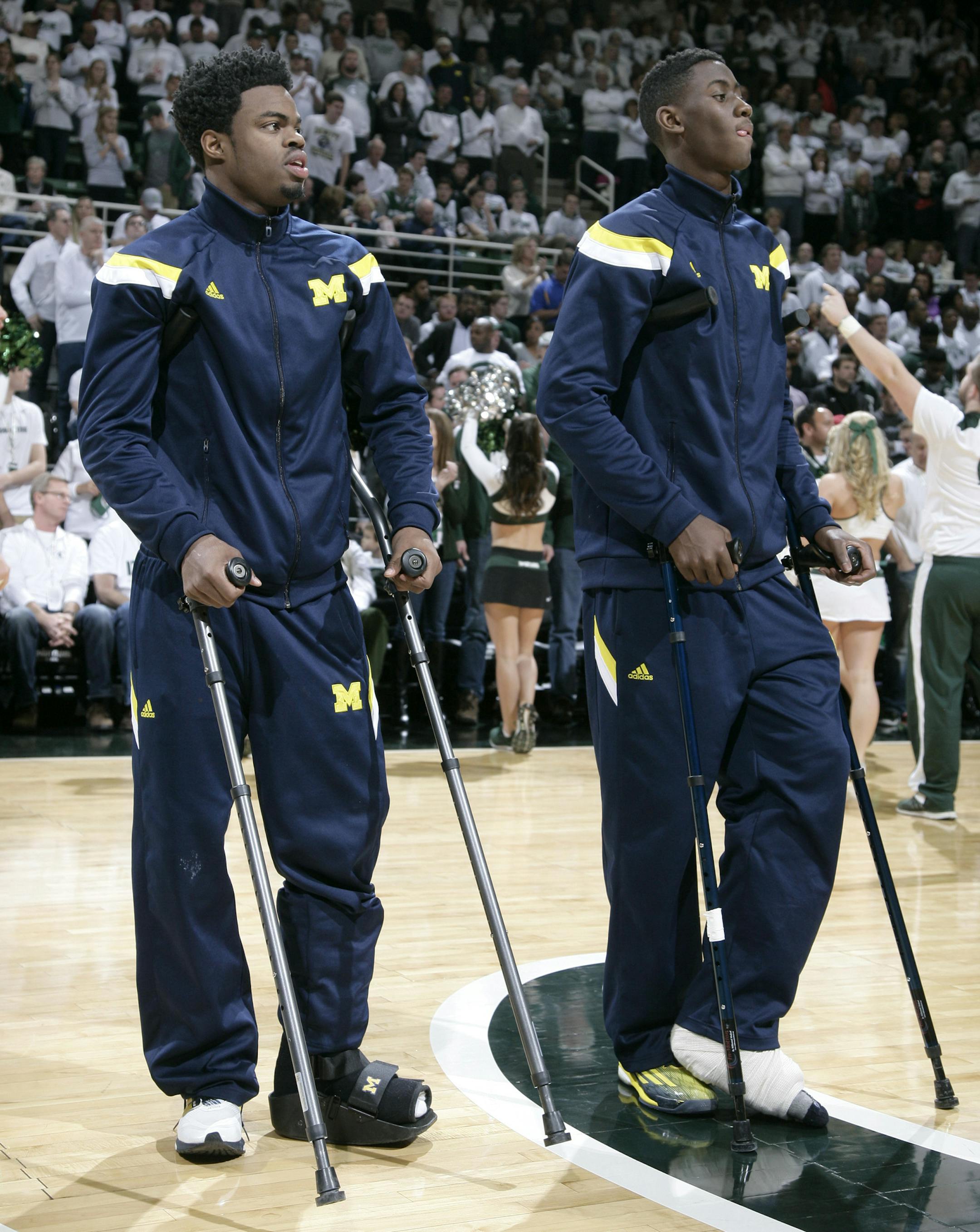 Injured Michigan players Derrick Walton Jr., left, and Caris LeVert watch warmups while standing on crutches before an NCAA college basketball game against Michigan State, Sunday, Feb. 1, 2015, in East Lansing, Mich. Michigan State won 76-66 in overtime. (AP Photo/Al Goldis) ORG XMIT: MIN2015022015463029