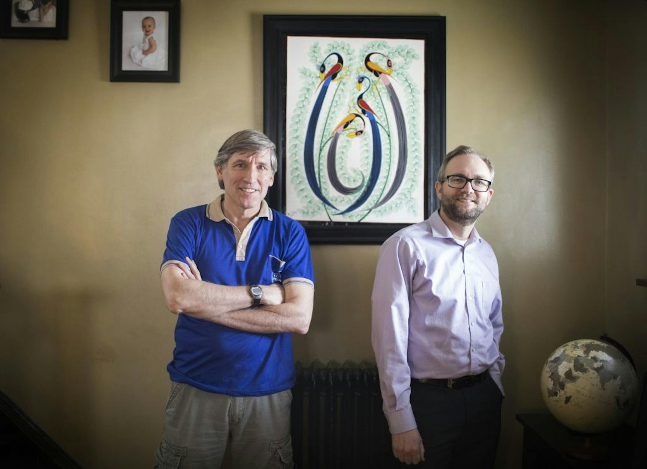 Ian Keith, left, and Brian Singer pose for a portrait in front of a Tingatinga painting that Brian bought in Tanzania.