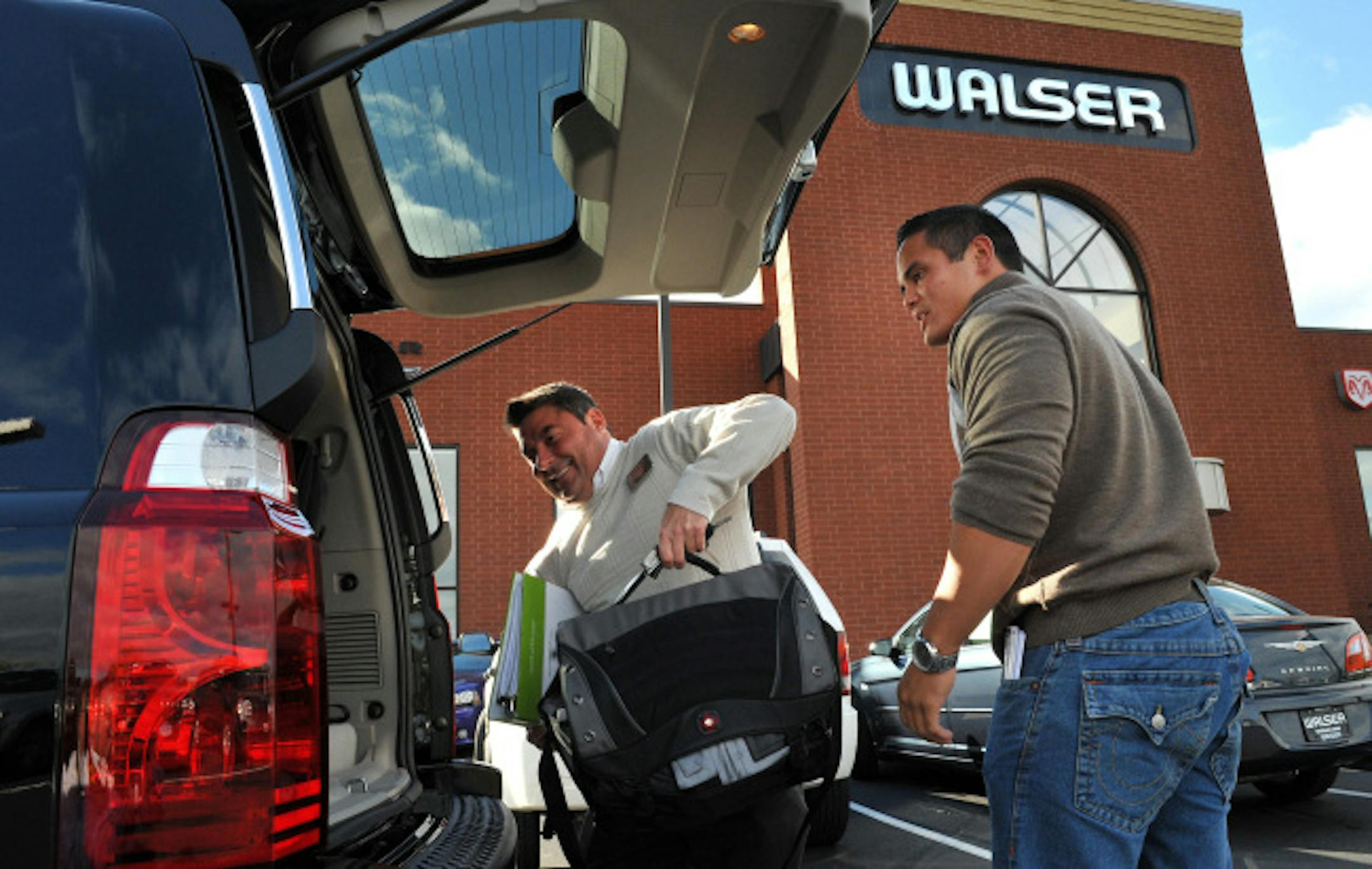 Patrick Hertel of Apple valley, right, on Wednesday bought a new Jeep Commando at Walser Chrysler Jeep Dodge in Hopkins. Internet sales manager Bobby Mauro helped him transfer his possessions from his old vehicle to the new one. Walser Automotive Group saw its sales fall off dramatically last month.