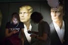 In this photo taken on Wednesday, Nov. 9, 2016, Maria Katasonova, left, looks at her smart phone during a live telecast of the U.S. presidential elect