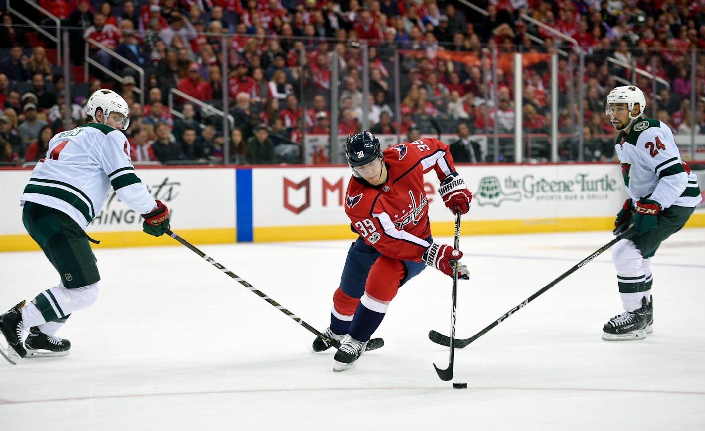 Minnesota Wild defenseman Mike Reilly (4) and defenseman Matt Dumba (24) battle for the puck against Washington Capitals right wing Alex Chiasson (39) during the second period of an NHL hockey game, Saturday, Nov. 18, 2017, in Washington. (AP Photo/Nick Wass)