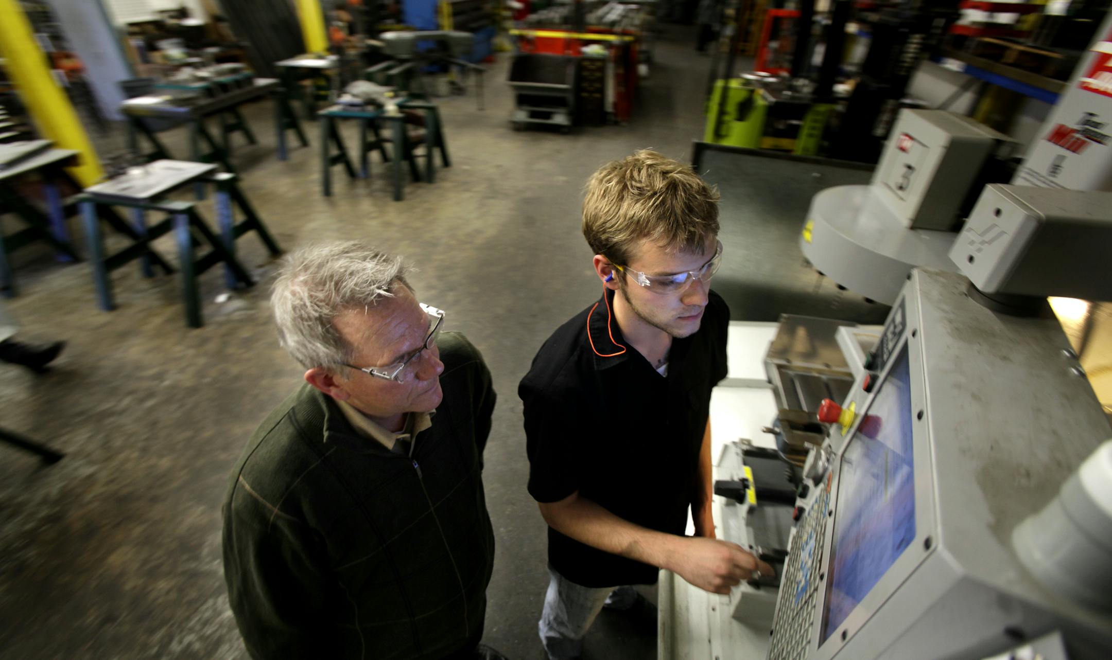 Dunwoody intern, Joe Brudzinski, (right), talks to Erick Ajax, co-owner of E.J. Ajax & Sons Inc., about a part that he was working on at the Fridley, MN plant on March 25, 2013. ] JOELKOYAMA‚Ä¢joel koyama@startribune.com Ajax at EJ Ajax & Sons in Fridley is hosting a Dunwoody College of Technology Da. They are celebraing the graduation of several employee/ apprentices into full journeyman status. This company is a metal stamper that trains folksin high tech manufacturing. It par