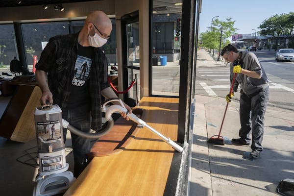 Jeff Neppl, left, and Megan Culverhouse, employees at John Fluevog shoe store in Uptown, cleaned up broken glass from a window that was hit by gunfire