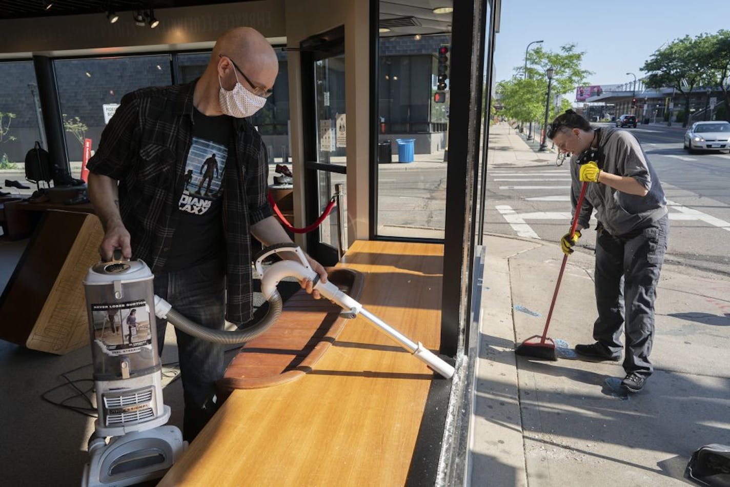 Jeff Neppl, left, and Megan Culverhouse, employees at John Fluevog shoe store in Uptown, cleaned up broken glass from a window that was hit by gunfire from an early morning shooting.