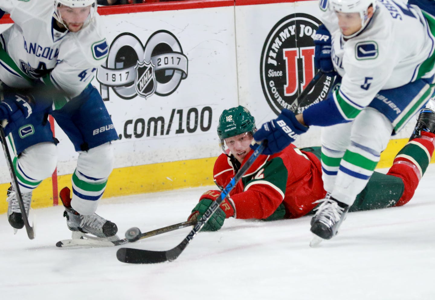 The Minnesota Wild's Eric Staal (12) goes to the ice and has the puck stolen by Vancouver's Sven Baertschi (47) and Luca Sbisa (5) .