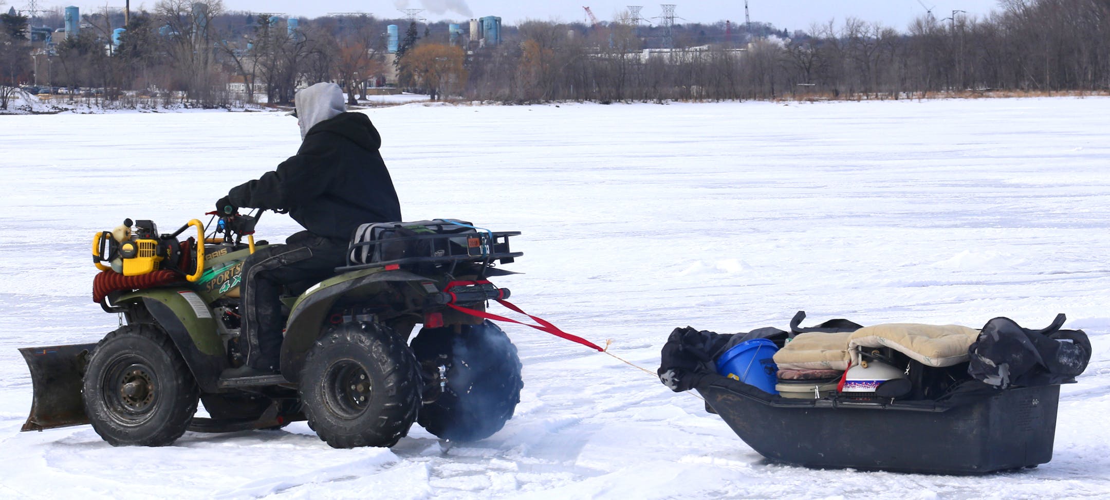 Self contained and self-reliant: Kyler Drews totes everything he needs to fish in winter, pulling a sled with his portable shelter behind his Polaris ATV. Drews plows snow in the winter, so when the white stuff isn't falling, he has time to drill a hole and fish.