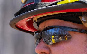 Jon Settergren, a Nisswa firefighter, talks with other firefighters and surveys the smoldered remains of a structure as part of the efforts to combat