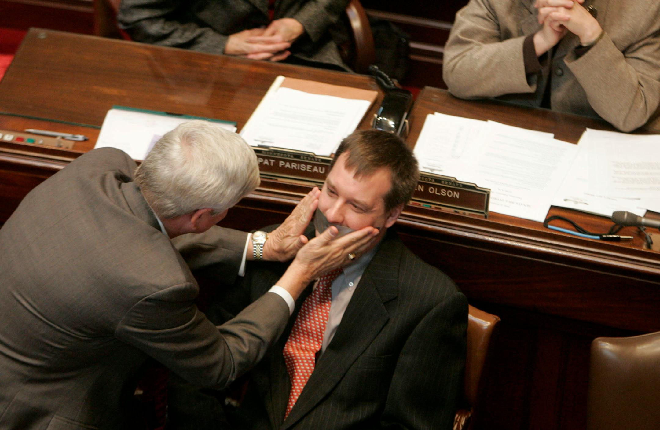 Sen. Dick Day, left, R-Owatonna, put tape on the mouth of fellow senator Chris Gerlach, R-Apple Valley, after Gerlach was admonished for straying from the rules during a floor discussion on Carol Molnau.