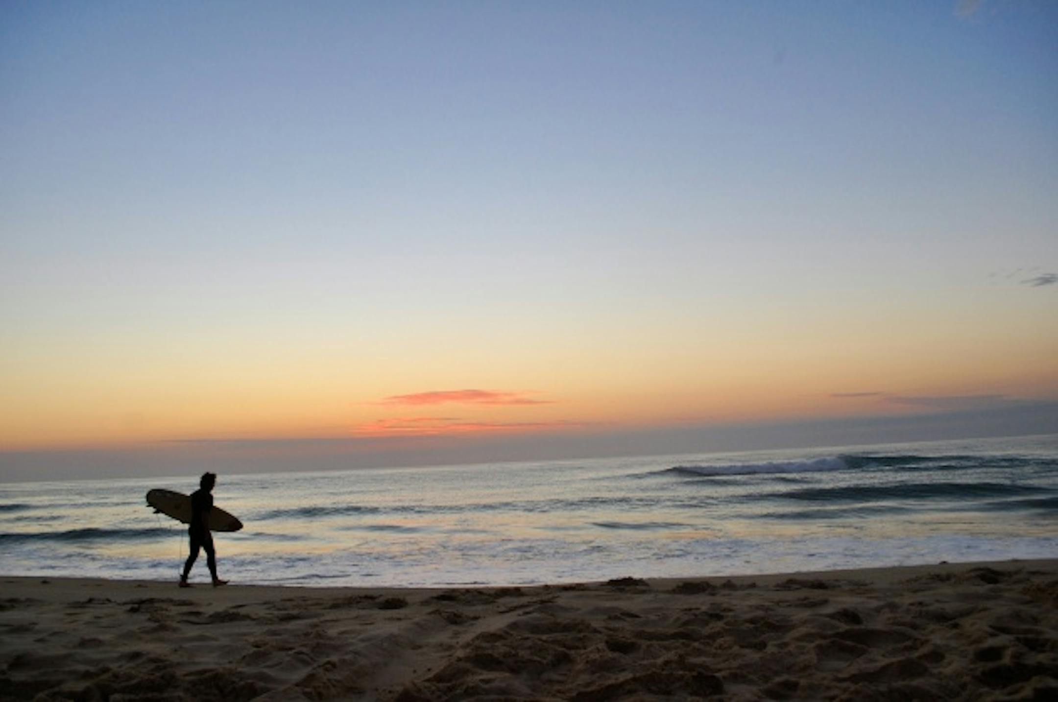 A surfer heading out before sunrise