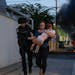 FILE - Police officers evacuate a woman and a child from a site hit by a rocket fired from the Gaza Strip, in Ashkelon, southern Israel, Saturday, Oct