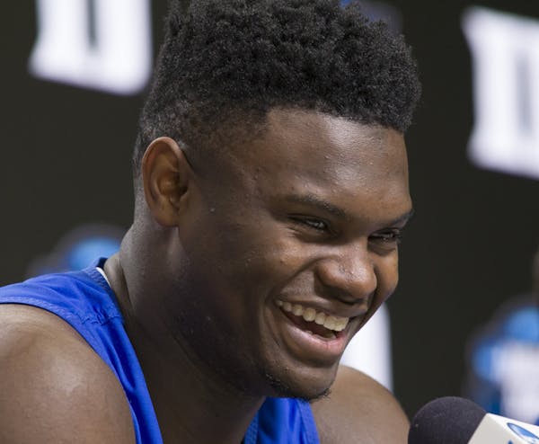 Duke forward Zion Williamson smiles as he speaks, accompanied by head coach Mike Krzyzewski, during an NCAA men's college basketball news conference i