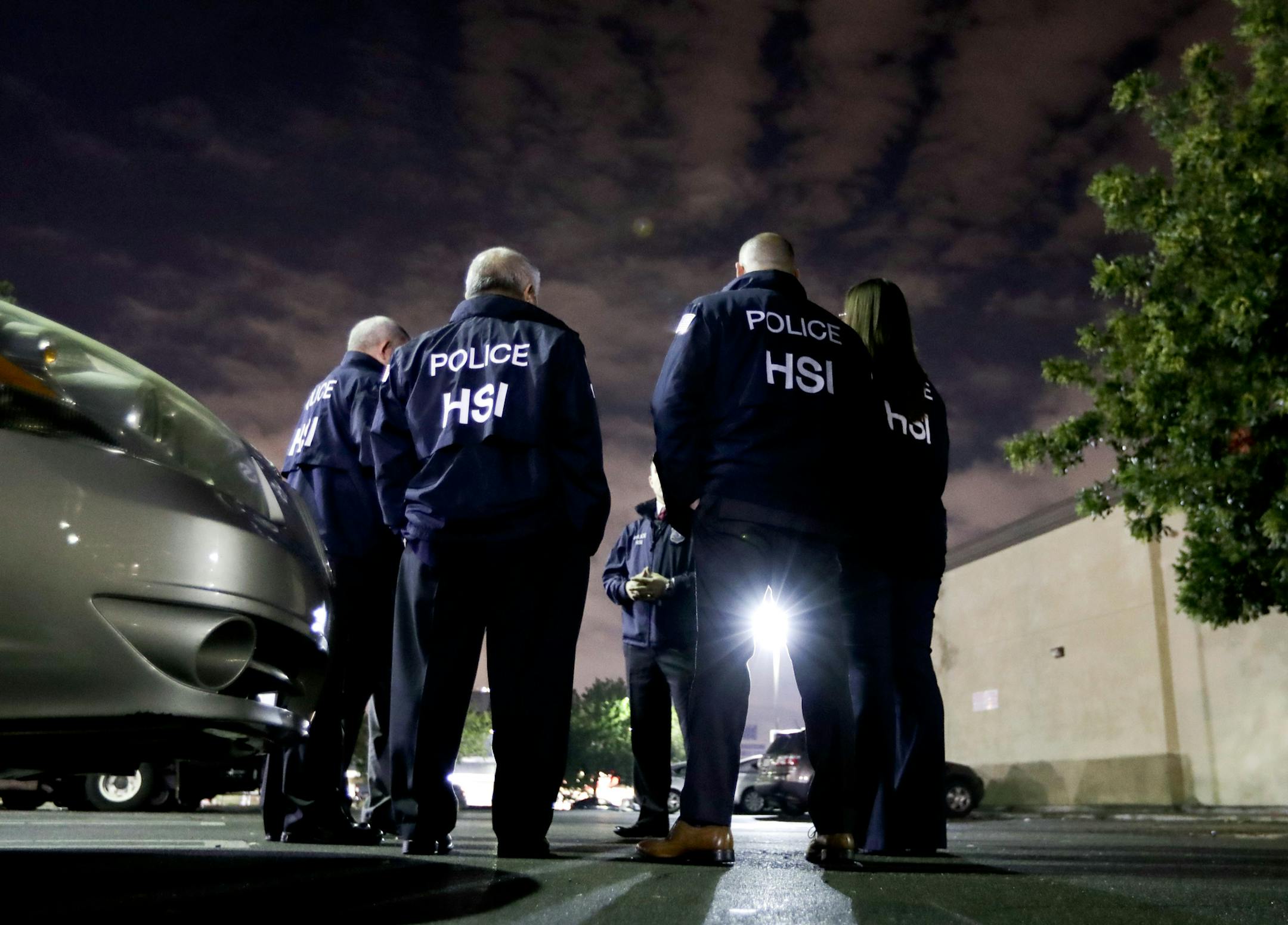 FILE - In this Jan. 10, 2018, file photo U.S. Immigration and Customs Enforcement agents gather before serving a employment audit notice at a 7-Eleven convenience store in Los Angeles. Immigration officials have sharply increased audits of companies to verify that their employees are authorized to work in the country, signaling the Trump administration's crackdown on illegal immigration is reaching deeper into the workplace to create a "culture of compliance" among employers who rely on immigran