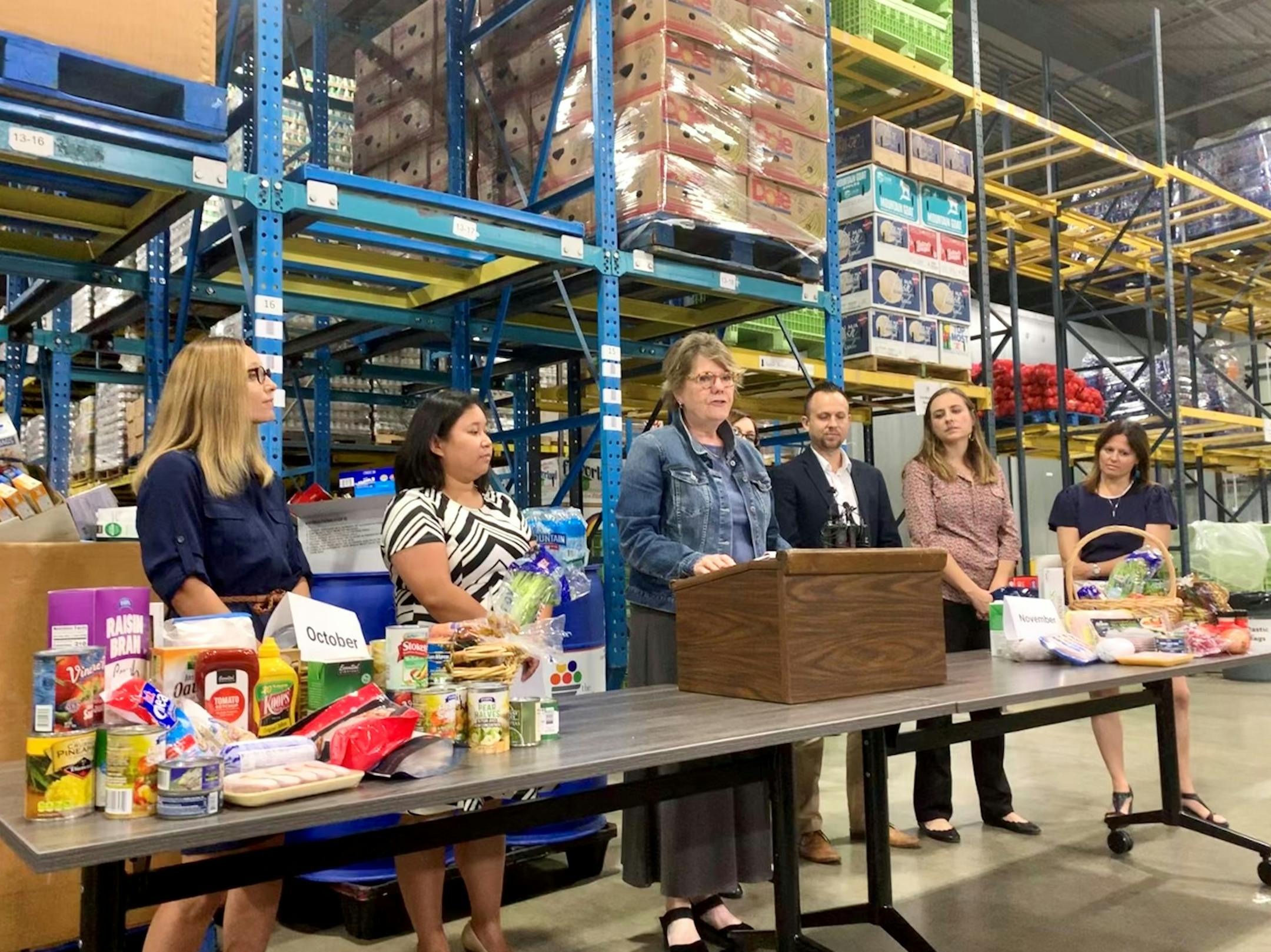 Colleen Moriarty, executive director of Hunger Solutions Minnesota (center), stood alongside other nonprofit leaders in opposition to the federal government's proposed SNAP changes, which would cut 35,500 Minnesotans off food assistance. The stacks of food illustrate how much food one family would lose a month.
