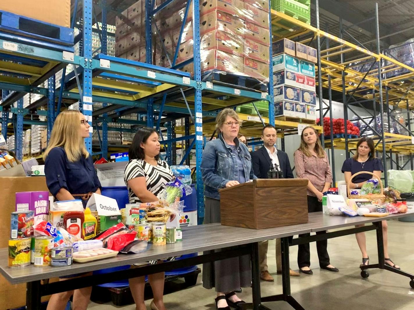 Colleen Moriarty, executive director of Hunger Solutions Minnesota (center), stood alongside other nonprofit leaders in opposition to the federal government's proposed SNAP changes, which would cut 35,500 Minnesotans off food assistance. The stacks of food illustrate how much food one family would lose a month.