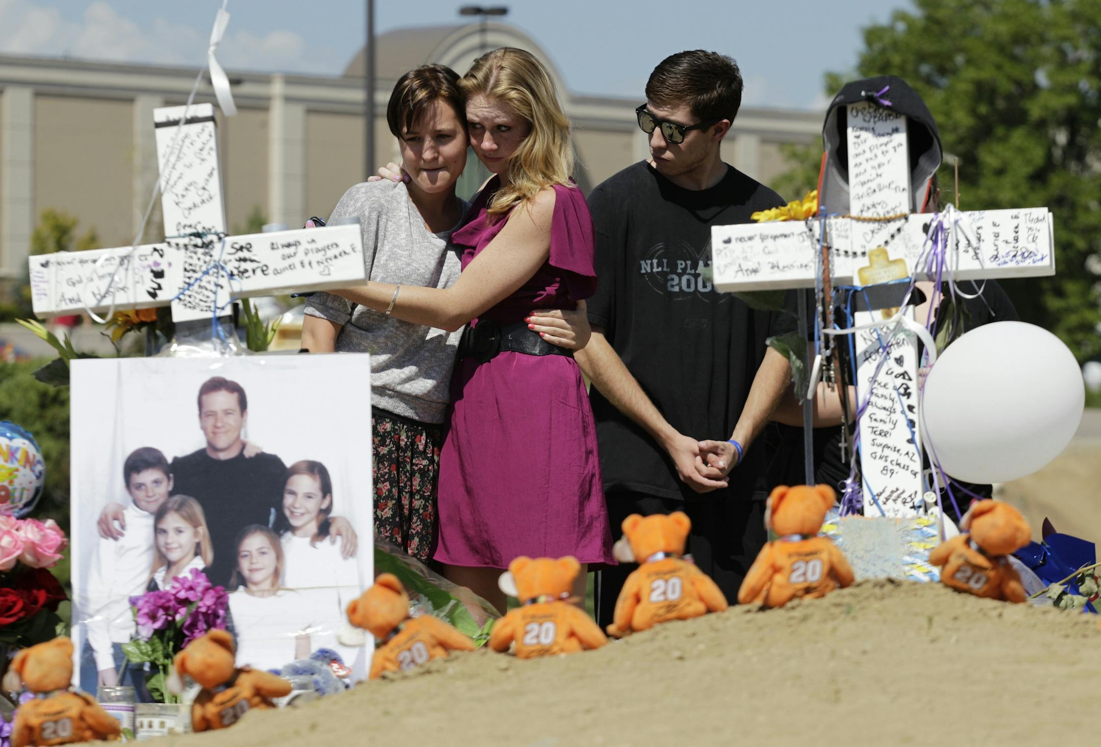 From left, Ashley Deuell, 18, Samantha Winslow, 18, and Michael Espinosa, 20, cry as they view crosses dedicated to Gordon Cowden, at left, and Alex "AJ" Boik, right), Tuesday, July 24, 2012 at a growing memorial to the victims of last Friday's mass shooting in a movie theater in Aurora, Colo. 12 people were killed, and dozens were injured in the shooting. Police have identified the suspected shooter as James Holmes, 24.