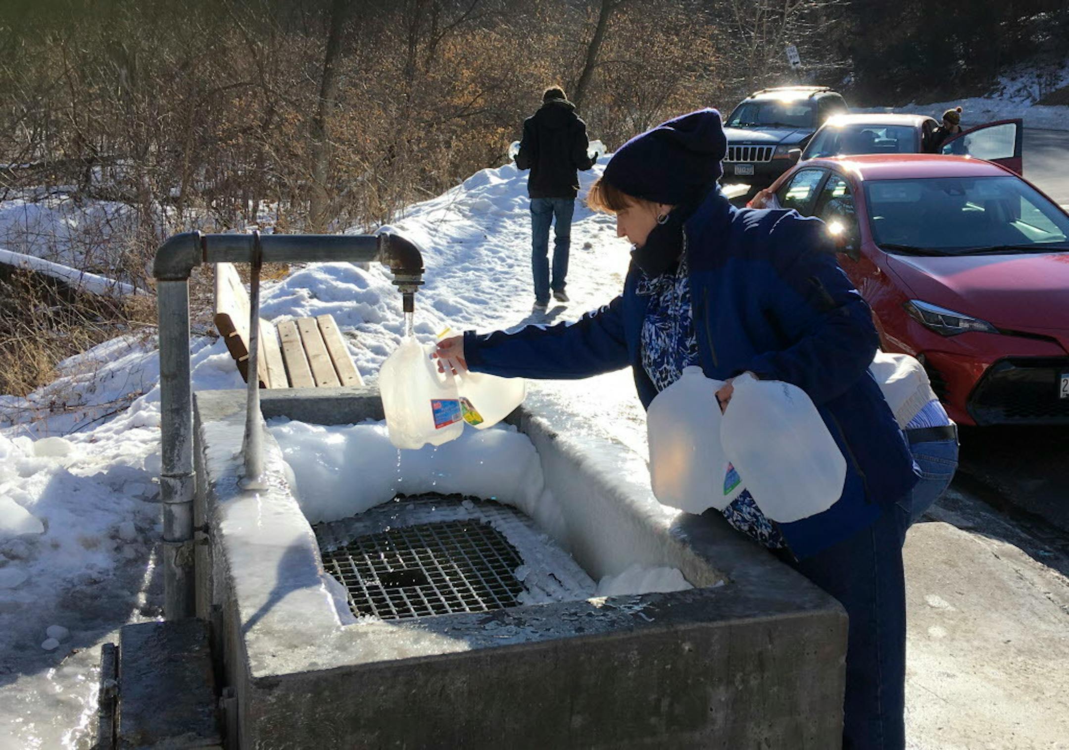 People lined up to fill water bottles from the Fredrick-Miller Spring in Eden Prairie. Although a sign warns that the city can't guarantee the safety of the water, "raw water" fans think that it tastes better than tap water, and some think that it's healthier.