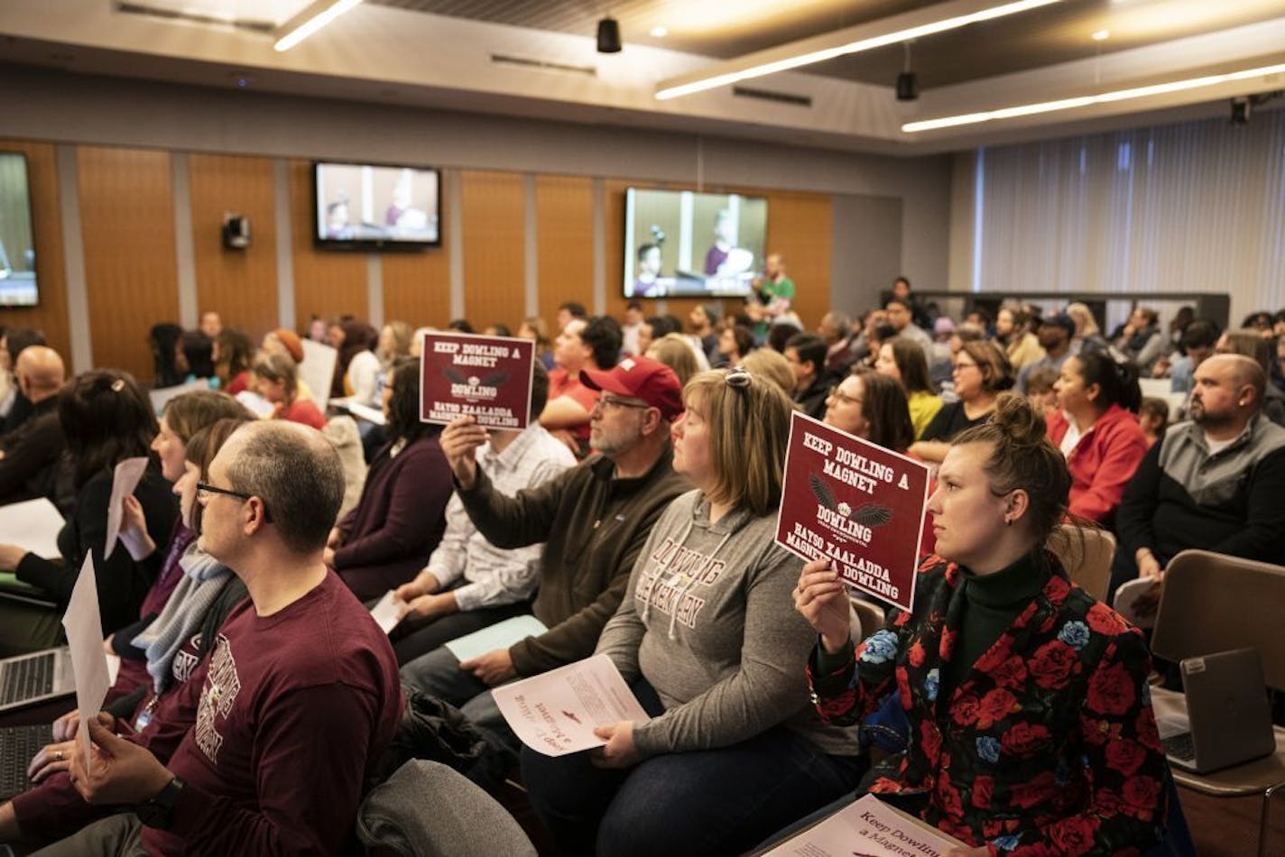 At right, Rachel Weeks held a sign supporting her child's school Dowling Elementary School, that is at risk from being closed with the proposed school restructuring plan, during the Minneapolis School Board meeting in Minneapolis, Minn., on Tuesday, February 11, 2020.