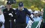 Jack Nicklaus and Gary Player wipe tears from their eyes as a chair is draped with a green jacket to honor Arnold Palmer before the start of the first