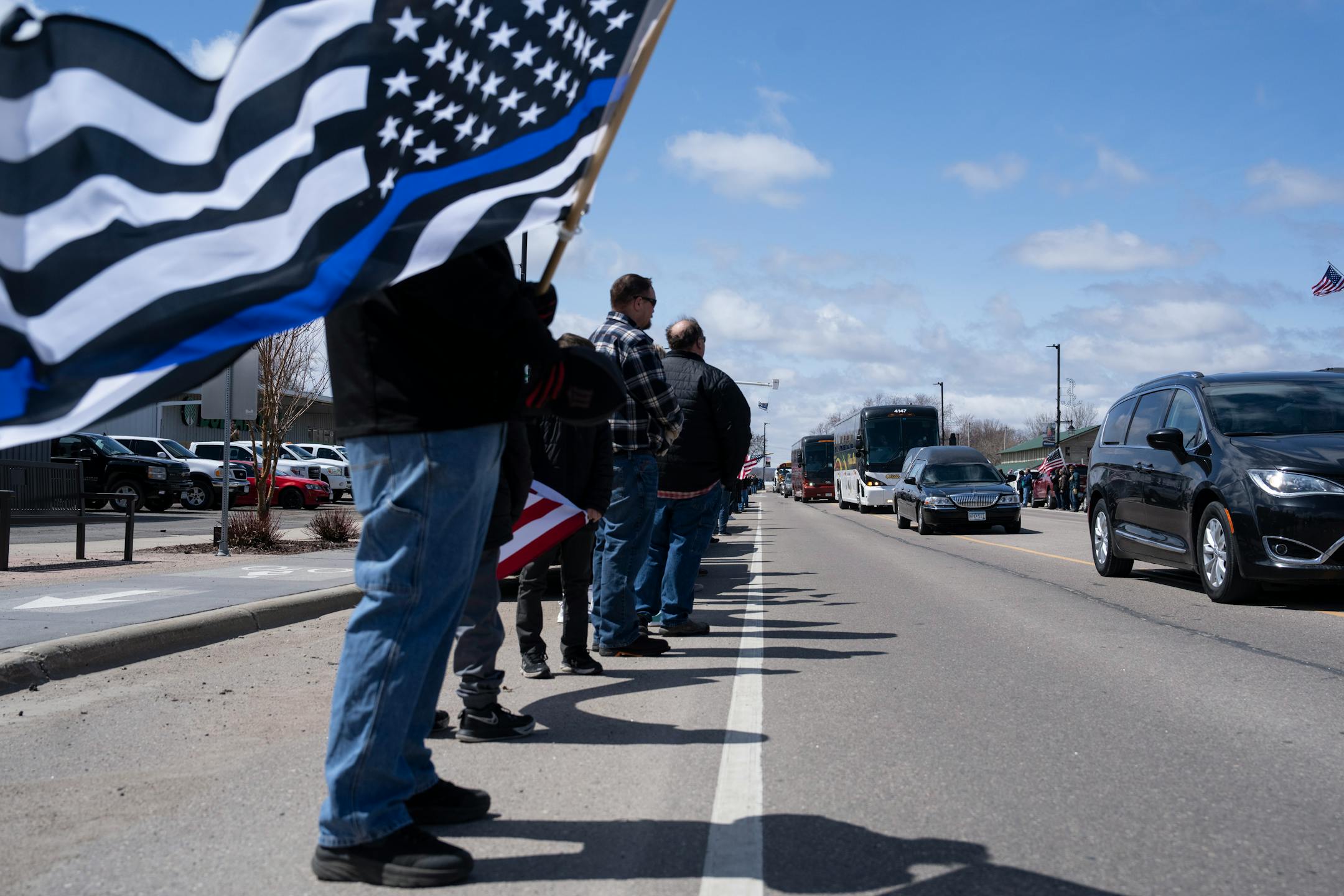 Ron Just holds a "thin blue line" flag during a funeral procession downtown Glendwood.