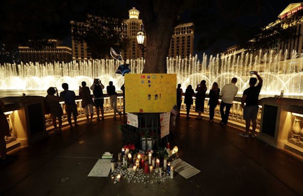 People take photos of the fountain at the Bellagio hotel in front of a memorial for victims of the mass shooting in Las Vegas, Tuesday, Oct. 3, 2017. 