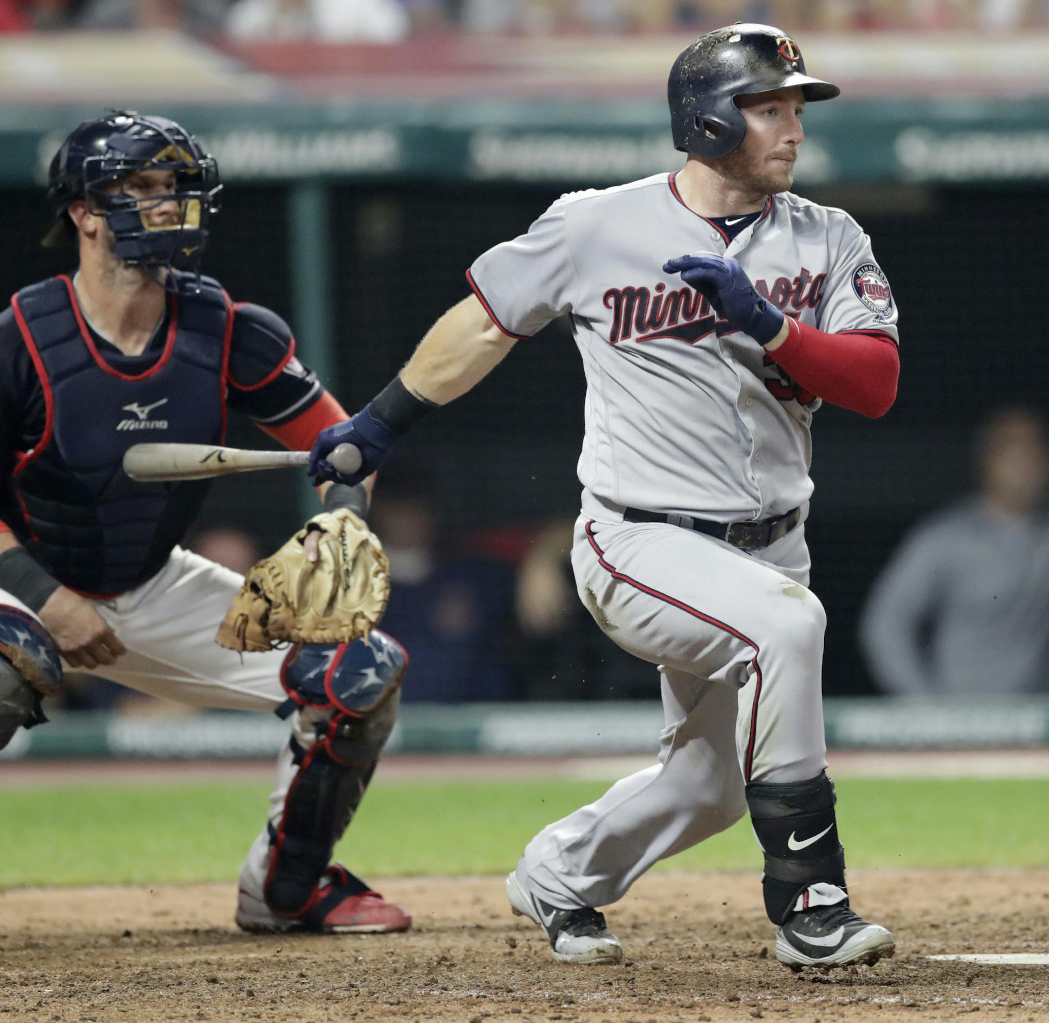 Minnesota Twins' Robbie Grossman watches his two-run single off Cleveland Indians relief pitcher Cody Allen during the seventh inning of a baseball game, Wednesday, Aug. 29, 2018, in Cleveland. At left is Indians catcher Yan Gomes. (AP Photo/Tony Dejak)