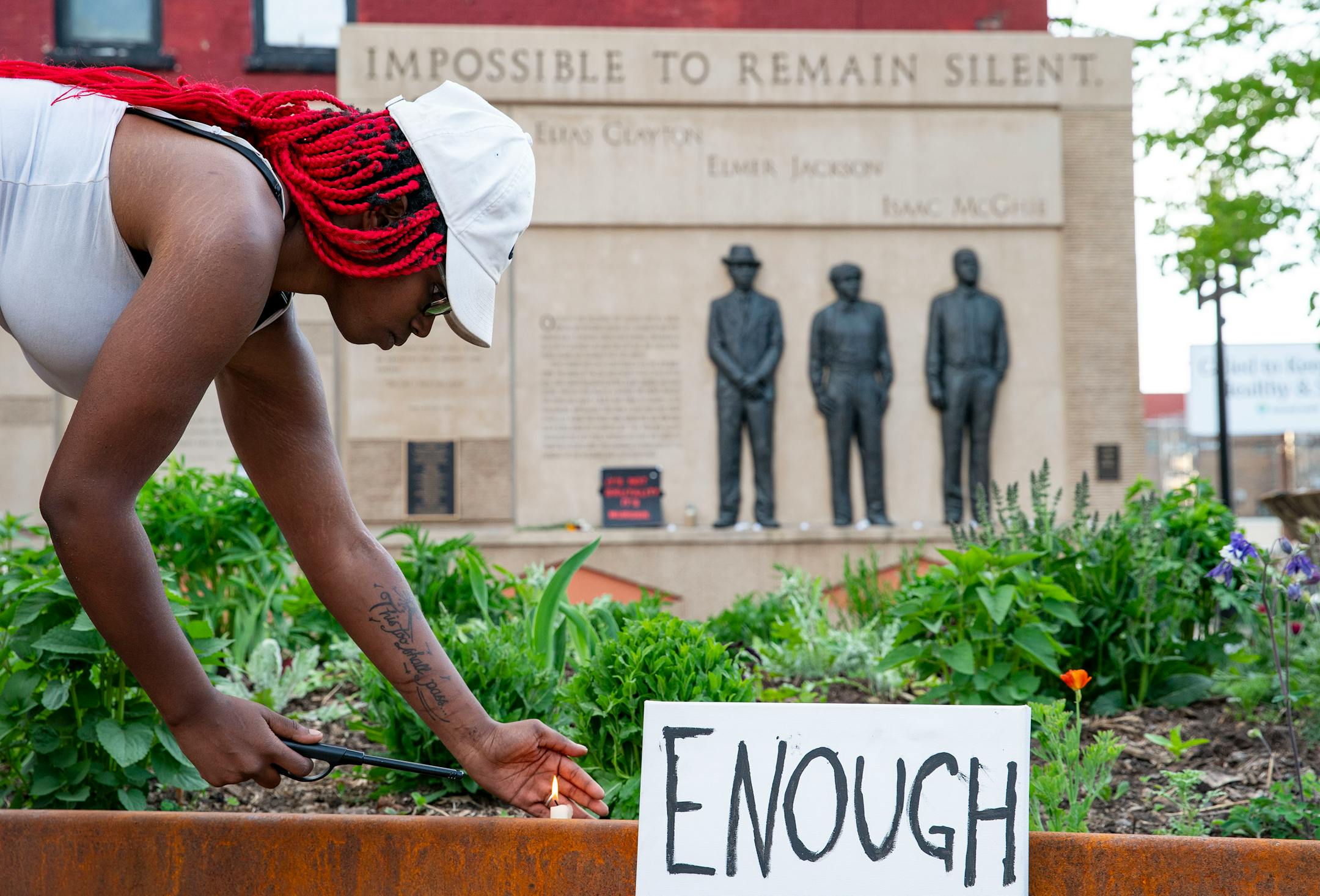 Quita Leach lit candles in front of the Clayton Jackson McGhie Memorial on June 3 in Duluth, MN. ]