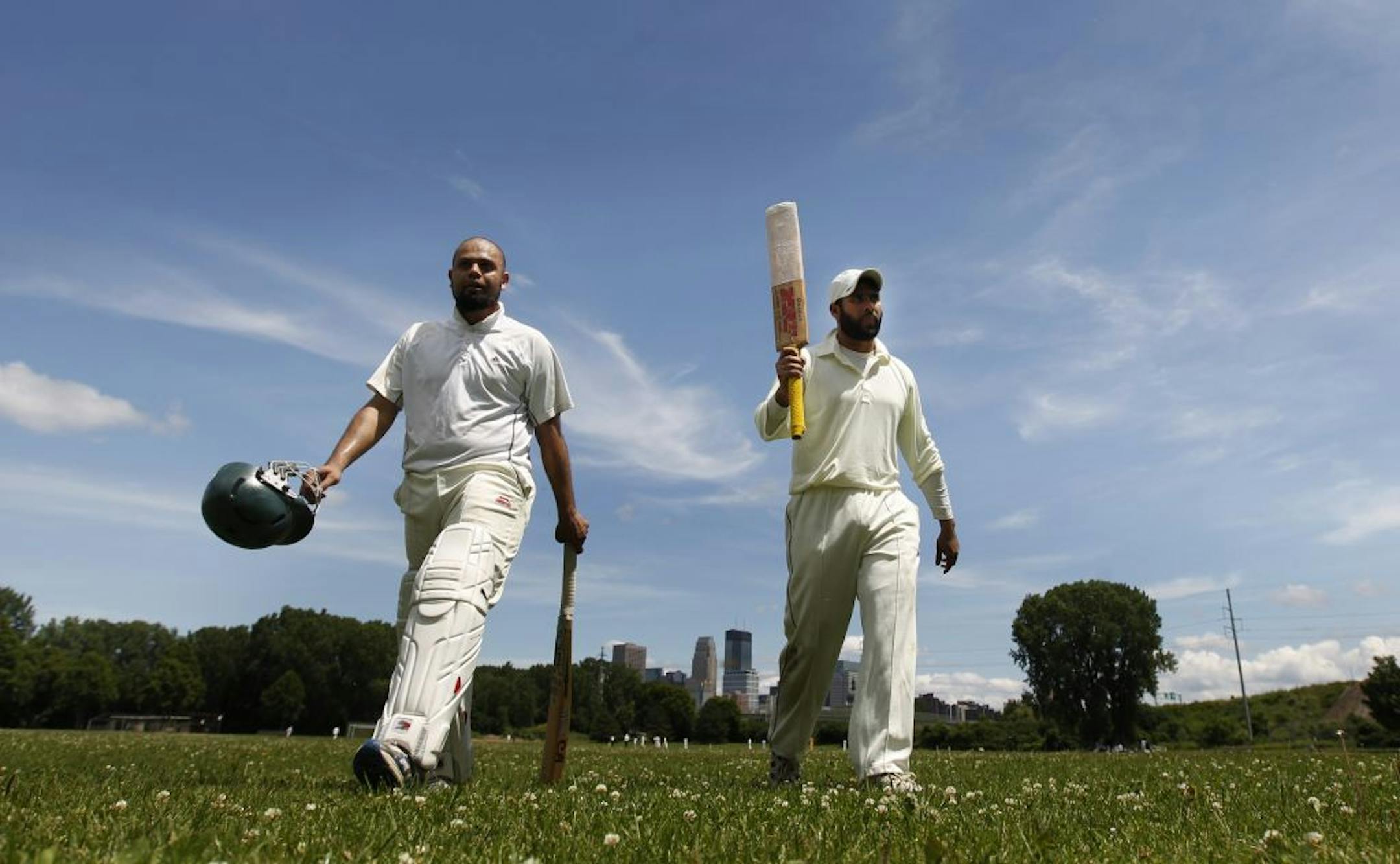 Hassan Mian, left, and Fawad Raza, the captain of the Strykers Reds cricket team, took a water break during a recent Sunday game at Bryn Mawr Park in Minneapolis.