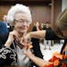 In this Sept. 23, 2013, Audrey Crabtree, 99, left, smiles as Sarah Dierks pins a 1972 East High homecoming pin onto her jacket during an during an edu