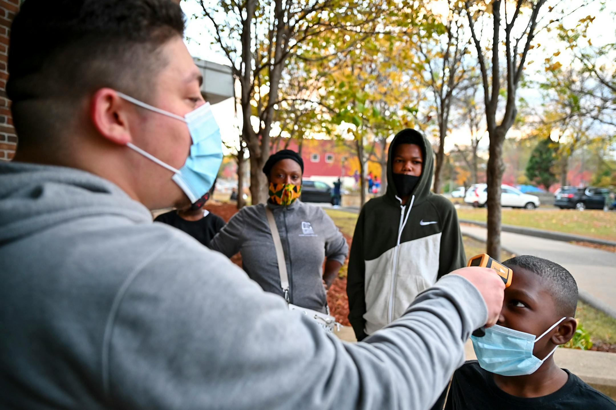West Side Boosters President Carlo Franco checked the temperature of Rico Williams, 8 before letting him inside El Rio Vista Recreation center Wednesday night for a basketball tryout.