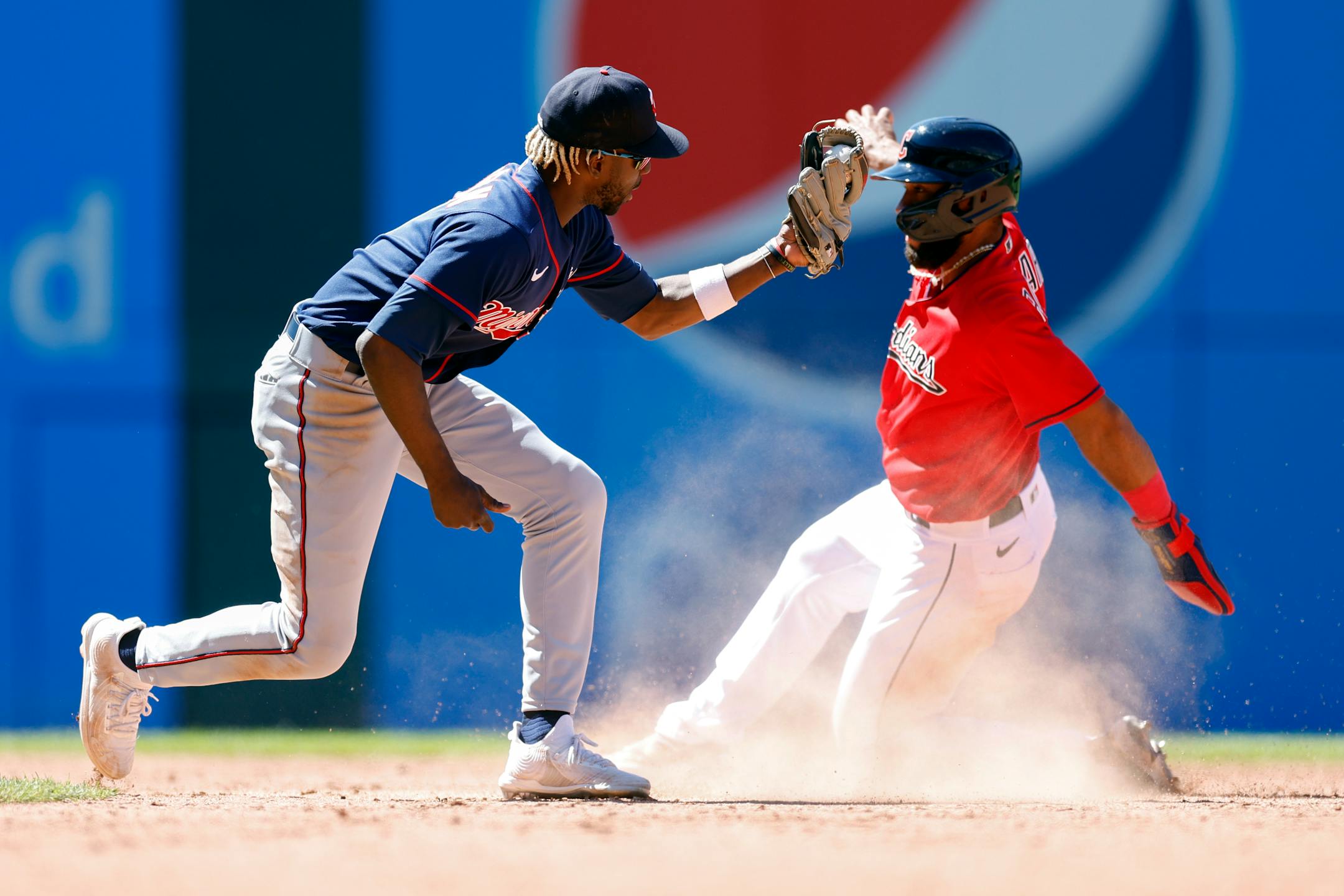 Minnesota Twins second baseman Nick Gordon, left, tags out Cleveland Guardians' Amed Rosario attempting to steal second base during the eighth inning in the first baseball game of a doubleheader, Tuesday, June 28, 2022, in Cleveland. (AP Photo/Ron Schwane)
