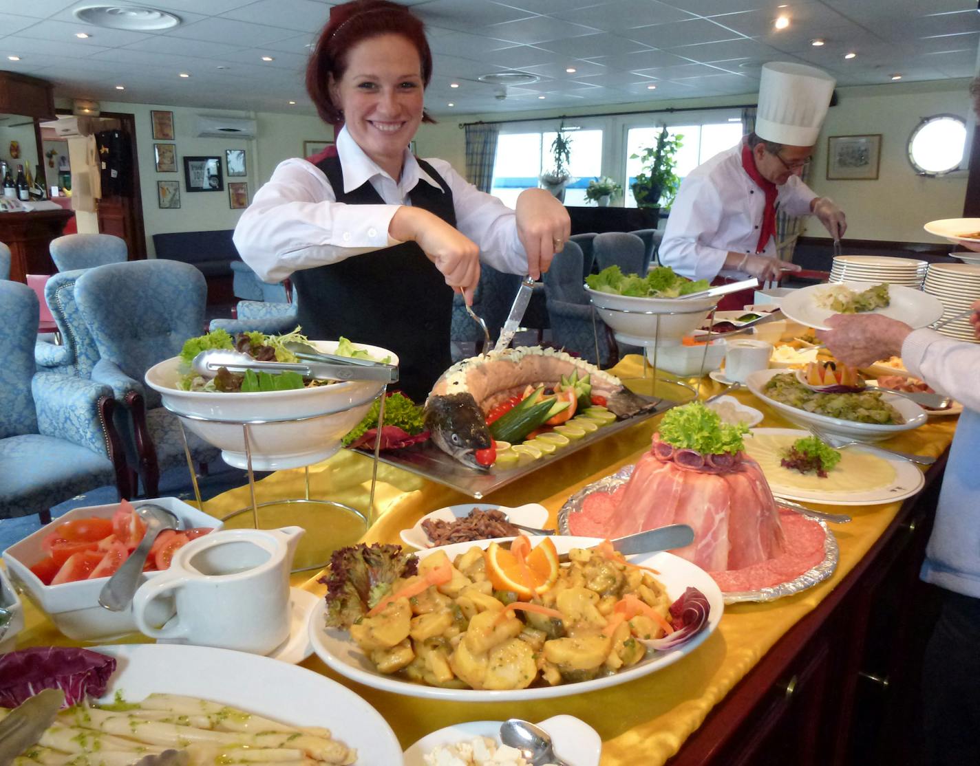 Bartender and server Melina Korsos preparing a lunch buffet, including a whole salmon. [ Photo by Pat Deckas Becerra Peg Meier takes a river cruise through France and discovers that pampering and knowledgeable guides can make a trip lots better. francetr070713