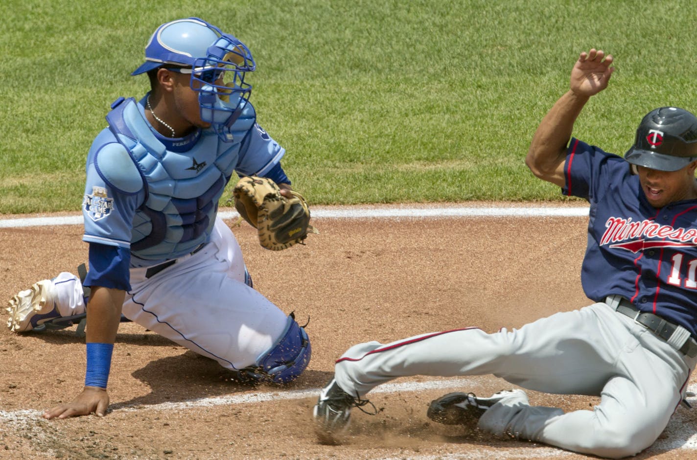 Minnesota Twins' Ben Revere (11) slides home past Kansas City Royals catcher Salvador Perez during the third inning of a baseball game at Kauffman Stadium in Kansas City, Mo., Sunday, July 22, 2012.