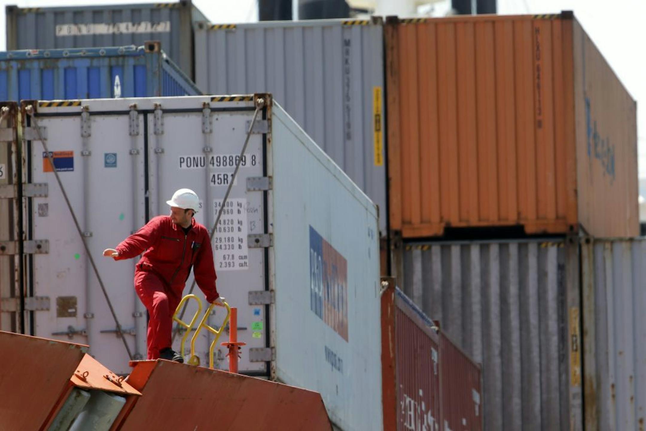 In this Tuesday, May 14, 2013 photo, a sailor on the Bahia Castillo, a Hamburg SUD-operated refrigerated cargo ship carrying fresh Chilean fruit and other goods, signals as it docks at Packer Avenue Marine Terminal, in Philadelphia.