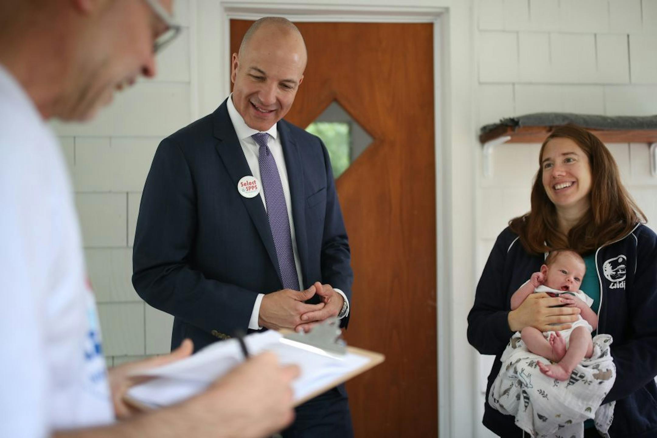 Nick Faber, president of the St. Paul teachers union, left, and Superintendent Joe Gothard spoke with Keely Young-Dixon who held her 1-week-old daughter Izzy Trotter about schools Thursday in St. Paul.