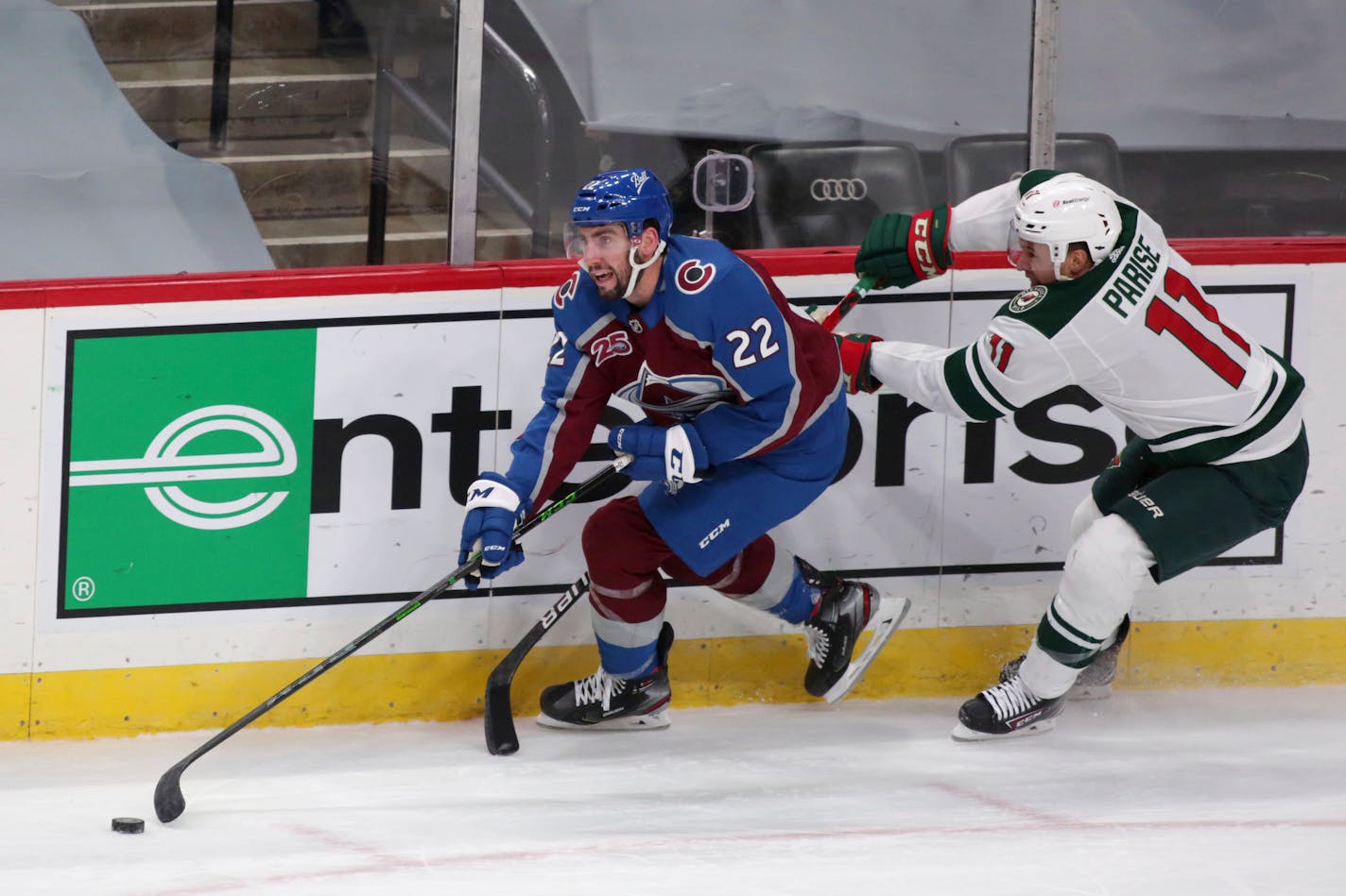 Colorado defensemen Conor Timmins controls the puck in front of Wild forward Zach Parise in the second period