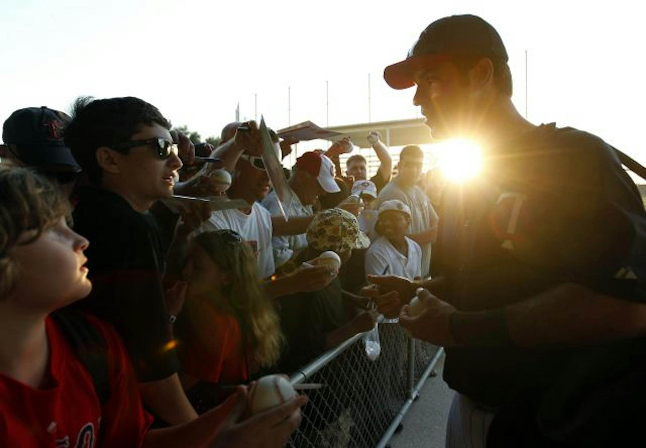 Twins catcher Joe Mauer signed autographs for young fans before Sunday's spring training opener against Boston. Mauer, easing into the spring, sat out the game.