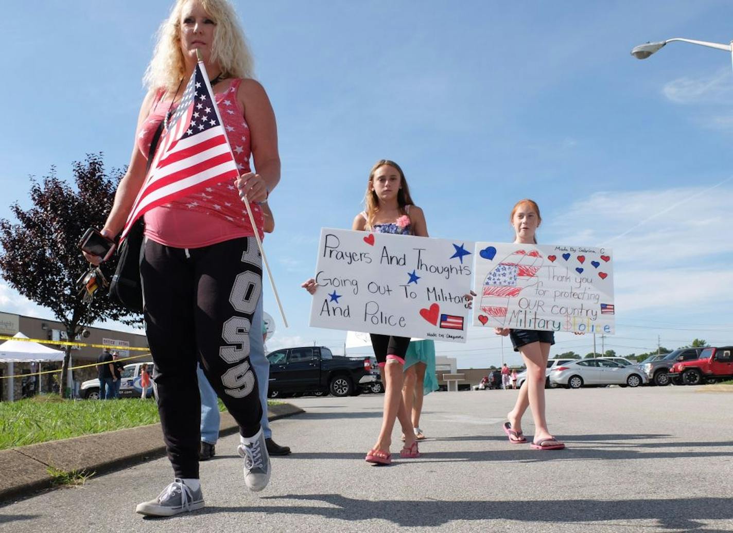 Crissy Essex, left, 44, Sabrina Cupell, and Cheyenne Essex bring signs and an American flag to a memorial near where a gunman fired shots into the Armed Forces Career Center, Thursday, July 16, 2015. A gunman unleashed a barrage of fire at a recruiting center and another U.S. military site a few miles apart in Chattanooga on Thursday, killing at least four Marines, officials said. The attacker was also killed. (Tim Barber/Chattanooga Times Free Press via AP) THE DAILY CITIZEN OUT; NOOGA.COM OUT;